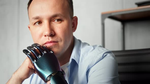 Serious cyborg disabled man with bio prothesis thinks holding head on hands