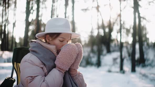 Beautiful Woman Drinks Hot Drink in the Woods in Winter Enjoying Camp Life