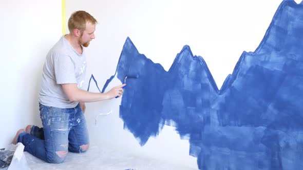 a man paints blue mountains on a bedroom wall