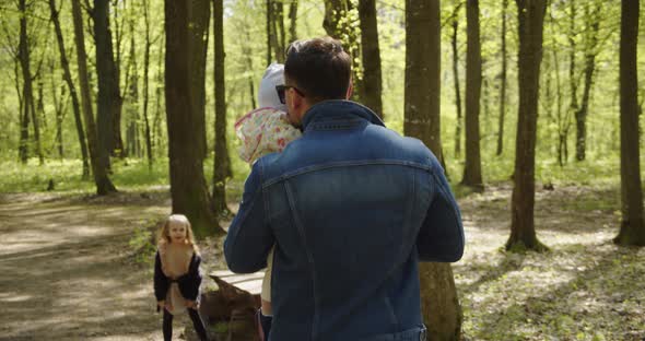 Little Happy Girl And Father With A Child In Their Arms Spend Time In Nature