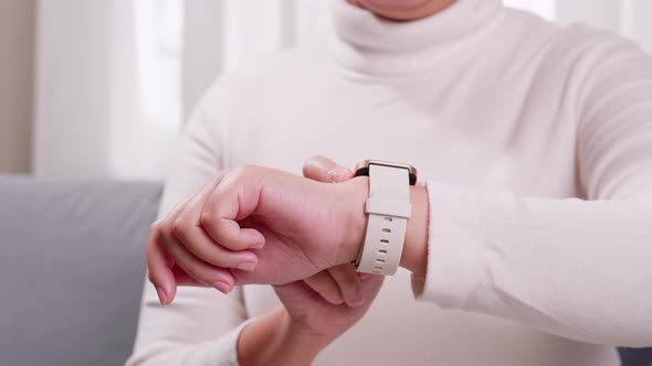 Close up shot of a woman hand who touch and scrolling on a smartwatch in order to quickly check appl