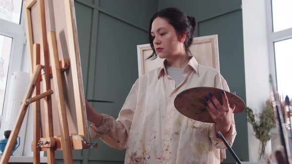 A Woman Artist in a Paintstained Shirt Painting in the Studio