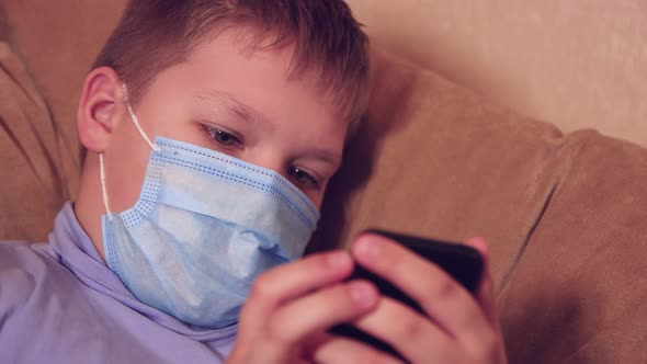 Happy Boy in a Mask on a Smartphone Plays Mobile Games