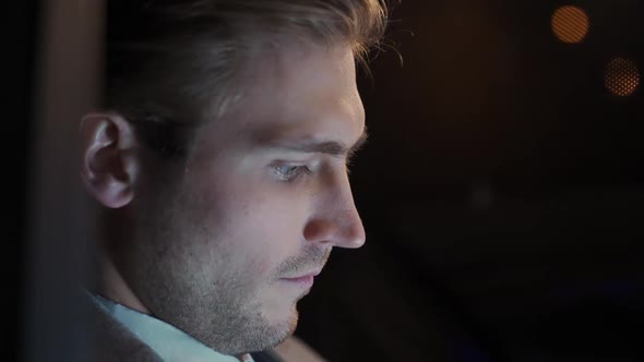 Portrait of a Young Businessman Sitting in a Moving Car and Using Laptop Man Top Manager in a Suit