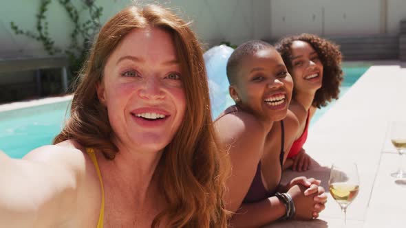 Diverse group of female friends having fun at pool taking selfie