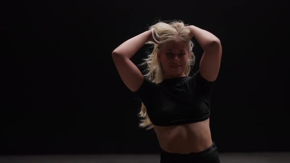 Alluring Young Woman Dancing in Studio Against Black Background