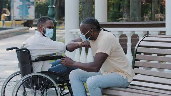 Two African American Men in Medical Masks Get Together Outdoors Greet Each Other with Elbows Abide