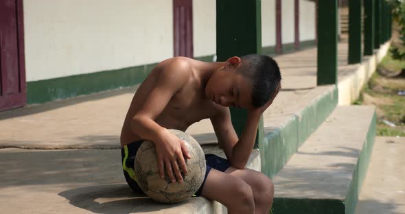 Sad Boy With Old Soccer Ball