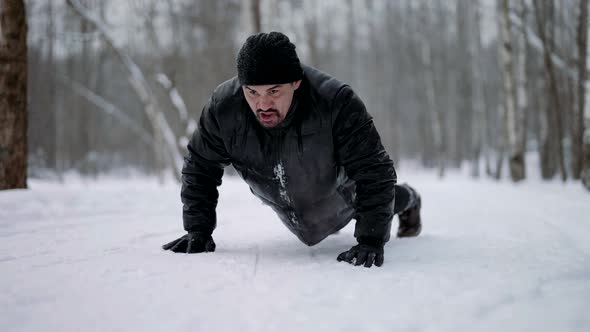 Workout for Endurance and Strength in Winter Forest Adult Athletic Man is Doing Pushup