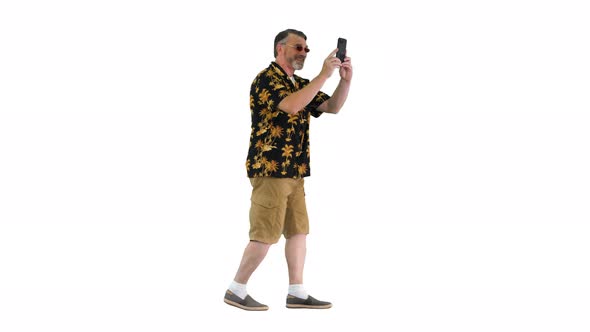 Happy Senior Bearded Tourist Man Walking and Taking Pictures with His Phone on White Background