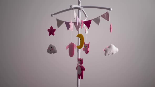 Baby Mobile with Pink Handstitched Animal and Bird Toys with Yellow Moon on White Wall Background