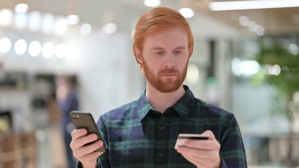 Portrait of Online Payment Success on Smartphone By Beard Redhead Man 