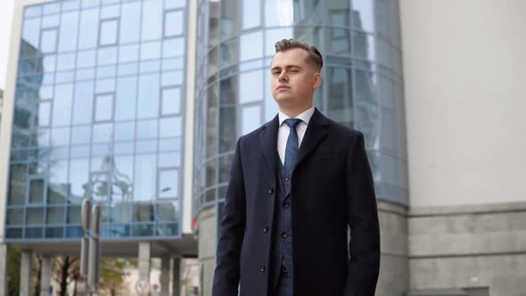 Stylish Elegant Male Businessman in Blue Jacket and Coat Near Office Center Looking at the Camera