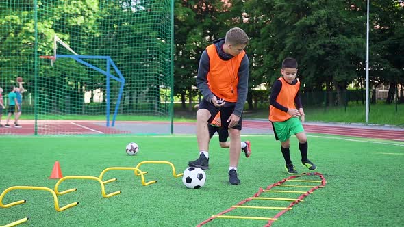 Football Players Doing Running Exercises with Obstacles Under Surveillance