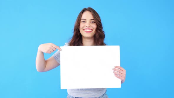 Beautiful woman holding blank placard on blue background