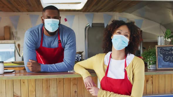 Portrait of african american couple wearing face masks standing near the food truck