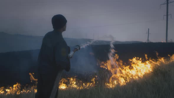 A Real Firefighter Extinguishes a Burning Flame From a Hose with Water