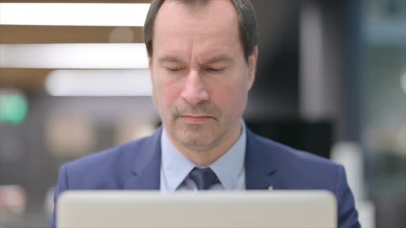 Portrait of Businessman with Laptop Looking in Camera