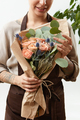 Smilling girl florist with creative bouquet from fresh flowers roses in a paper on a light - PhotoDune Item for Sale