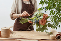 Female florist is decorating beautiful bouquet from fresh natural roses step by step at the table - PhotoDune Item for Sale
