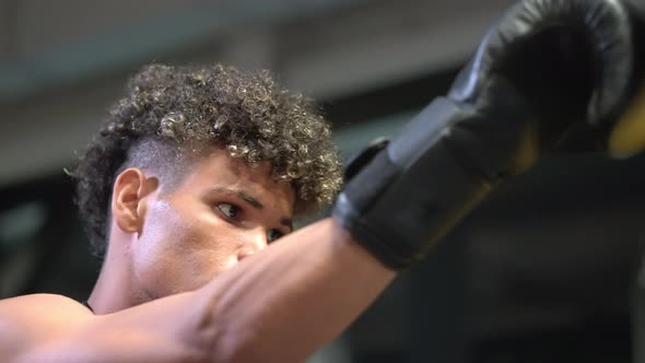 Boxing Training in Gym Young Black Prizefighter is Punching Punchbag in Training Room