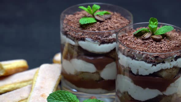 Classic Tiramisu Dessert in a Glass and Savoiardi Cookies on Dark Concrete Background