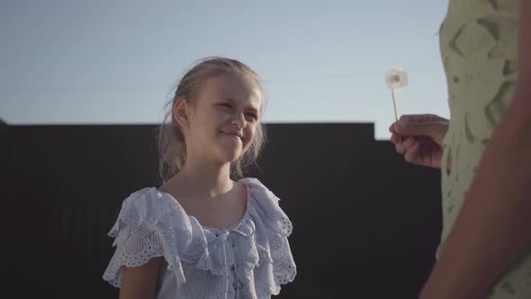Nice Kind Daughter Giving Her Mother a Dandelion Flower and Smiling at Her in Summer Evening