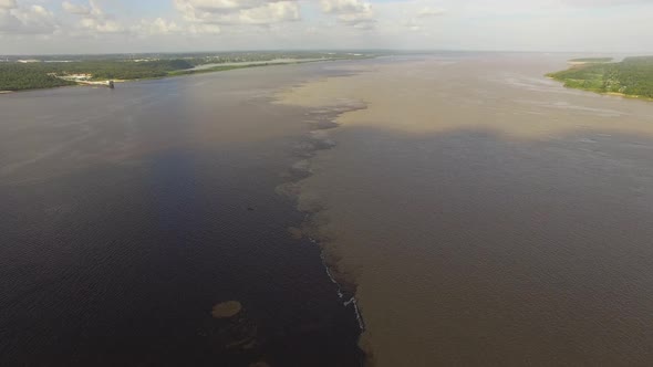 Cinematic high aerial shot over the meeting of the Black River and the Amazon River