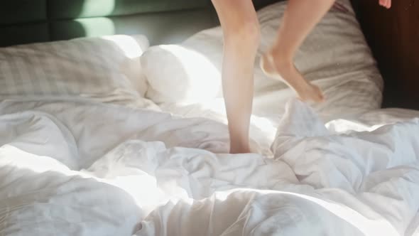 Child's feet jumping on the bed in the morning. Kid has fun frolicking and playing