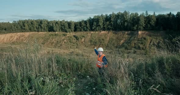 Working Engineer in a White Helmet Next to a Sand Pit