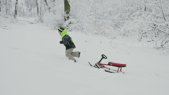 Guy Hat Running on a Snow-Capped Mountain and Entails Sledding