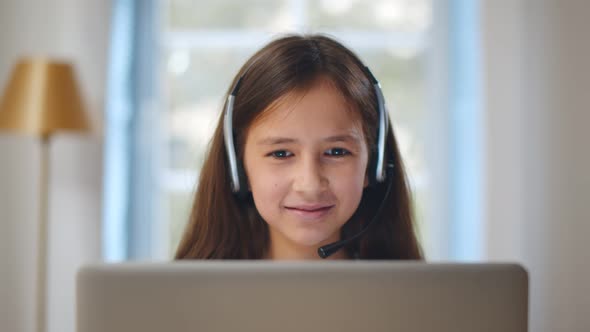 Portrait of Child Girl in Headset Using Laptop and Study Online at Home