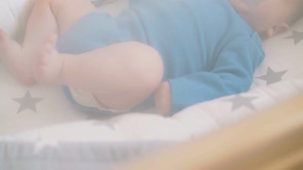 Newborn Child Kicks Bare Legs Sucking Pacifier in Cocoon