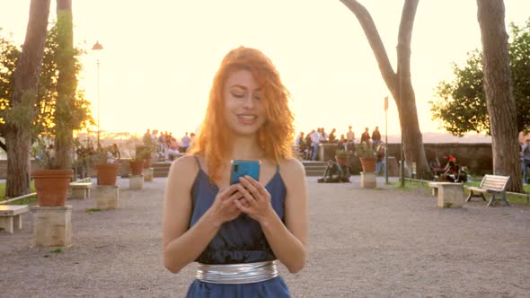 media, globalization-woman reads a message walking in the giardino degli aranci