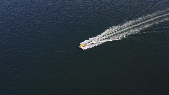 A Yellow Speedboat Sails at High Speed on the Surface of the Sea