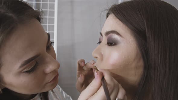 Makeup Artist Working with Brush on Beautiful Asian Girl Face