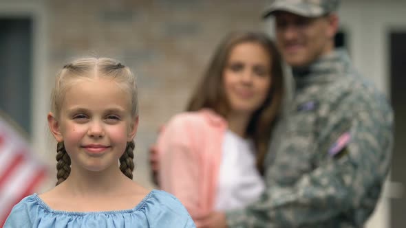 Smiling Girl Showing American Flag Patch, Hugging Parents on Background, Patriot
