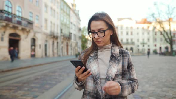 Woman Walking Down an Old Street and Using Smartphone