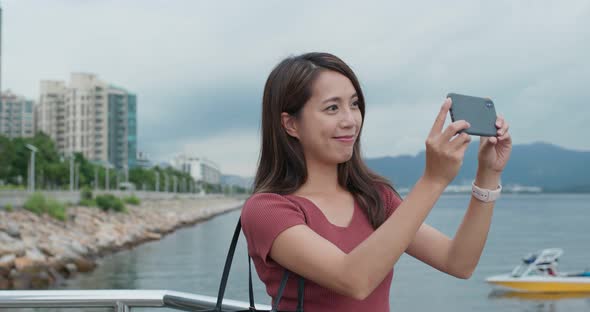 Woman use of mobile phone for take photo in the street