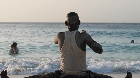 Athletic African Man Sits on Twine and Goes in for Sports on the Beach By Ocean