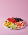 Set of different citrus fruits and berries in a plate presented on a pink background with copy space - PhotoDune Item for Sale