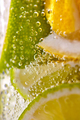 Macro photo of freshly made lemonade with pieces of lime, lemon and bubbles in a glass. Summer - PhotoDune Item for Sale