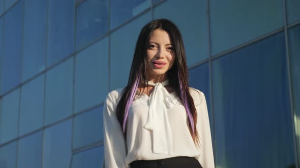 Young Businesswoman Smiling Walks Along Glass Business Center