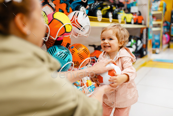 in kids store. Mom and child together choosing toys in supermarket, family shopping