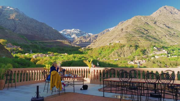 Tourist eating breakfast at the rooftop terrace in Imlil with Toubkal view, Morocco