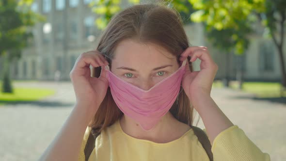 Close-up Portrait of Charming Young Woman Taking Off Face Mask and Smiling at Camera. Beautiful