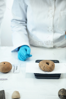 Archaeologist Measuring Prehistoric Weight on a Precision Scale in Laboratory