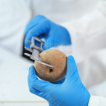 Archeology Scientists Measuring Prehistoric Artefact with Digital Caliper in Laboratory
