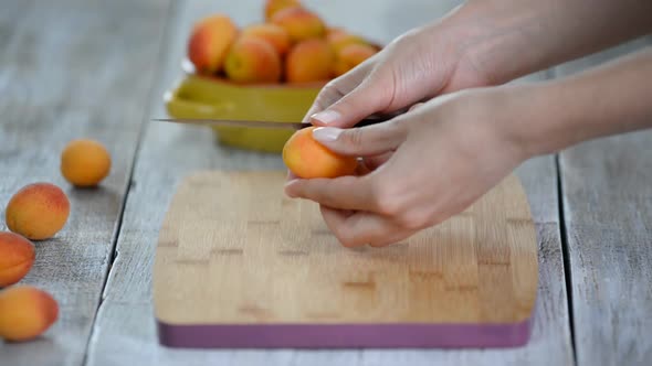 Close-up of female hands cutting apricots with a knife on a cutting board, Cooking Vegetaria