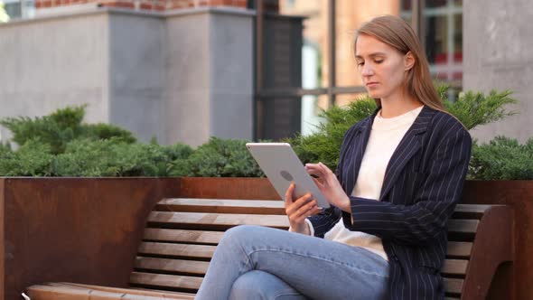Business Woman Browsing Internet on Tablet While Sitting Outside